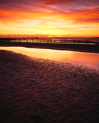 The sun sets behind a bank of cloud at West Wittering beach